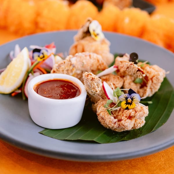 Crispy fried Indian appetizer with dipping sauce, lemon, and salad on a banana leaf.