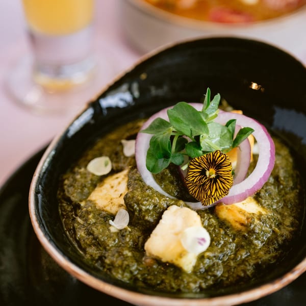 Saffron's Palak Paneer, a vibrant green Indian dish with cheese, onion, and edible flowers.