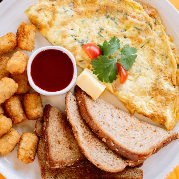 Saffron's Indian omelet with tater tots, toast, butter, and a side of red sauce.