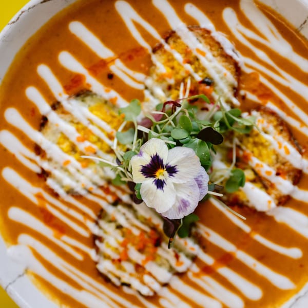 Overhead view of Saffron's Indian soup, garnished with cream, microgreens, and an edible flower.