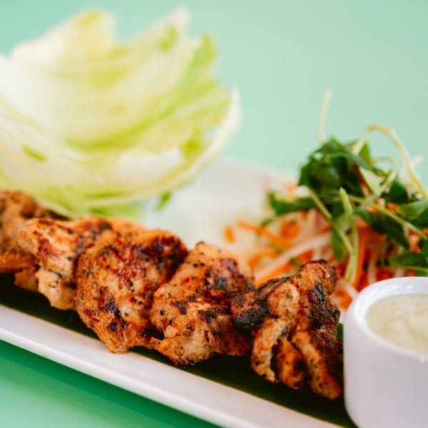 Grilled chicken tikka pieces with a side of salad, lettuce, and a dipping sauce.
